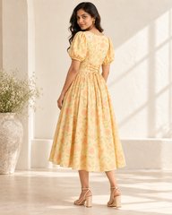 Adult Indian woman modeling the calf-length pastel-yellow floral cotton dress, back three-quarter view
