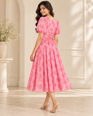 Adult Indian woman modeling the calf-length pink floral georgette dress, back three-quarter view